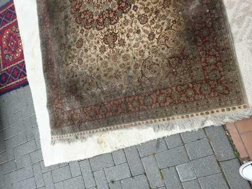 Auf einem gepflasterten Gehweg liegt ein Teppich.