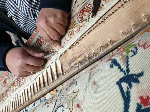 Eine Person bearbeitet einen Teppich mit einem Kamm.