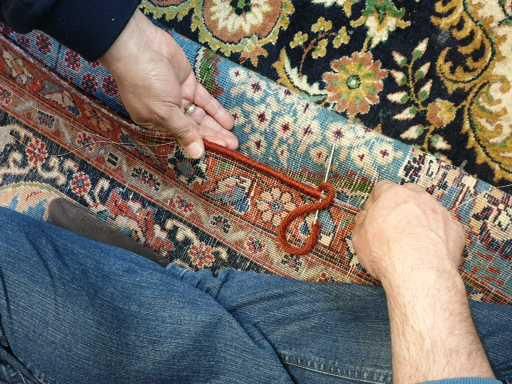 Eine Person bearbeitet einen Teppich mit einer Zange.