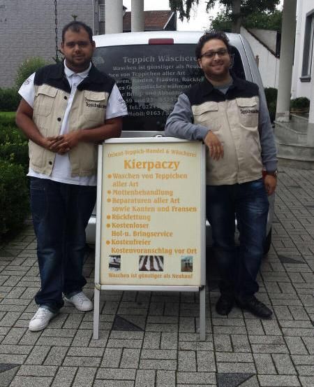 Teppichwäscherei Kierpaczy Zwei Männer stehen neben einem Schild mit der Aufschrift „klerpaczy“