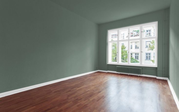 Una habitación vacía con paredes rojas y ventanas blancas.