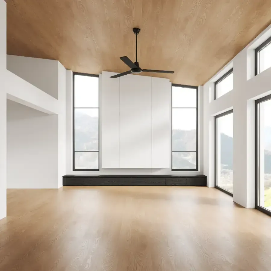 Una sala de estar vacía con un ventilador de techo y muchas ventanas.