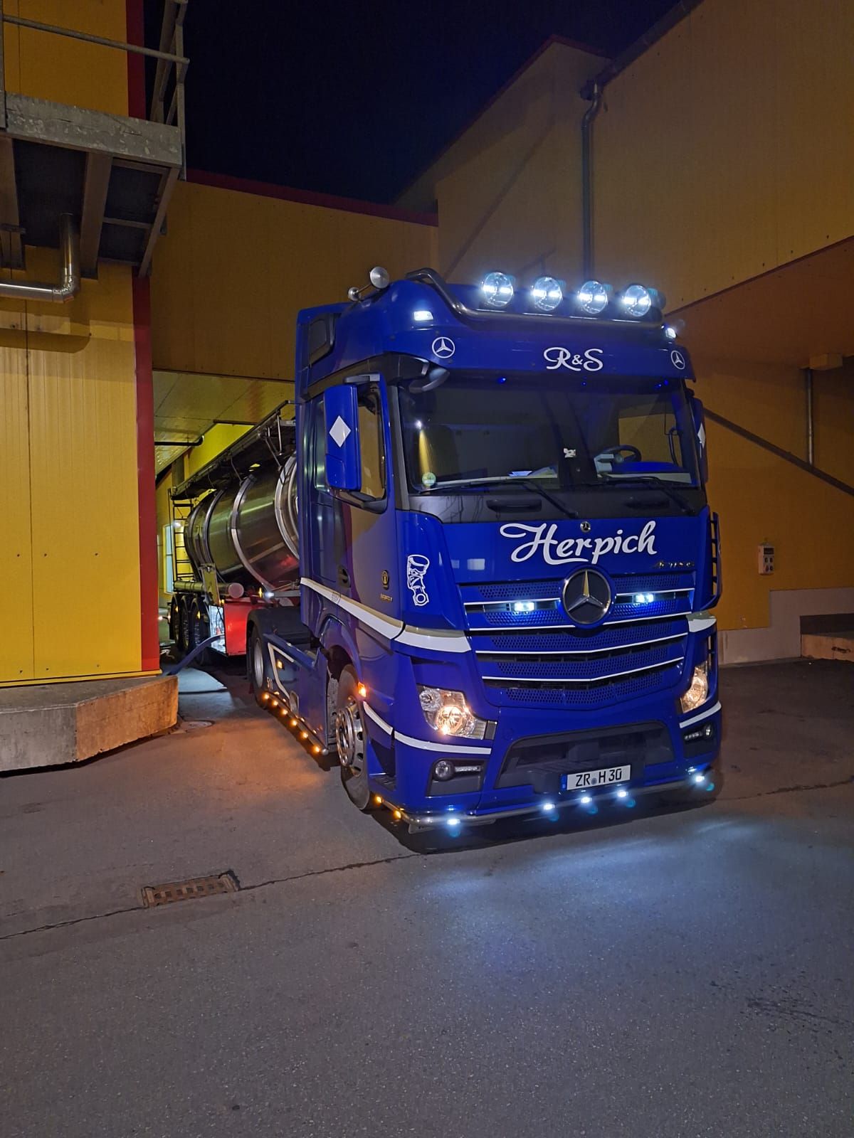 Blauer Herpich-LKW an einer Laderampe, beleuchtet.