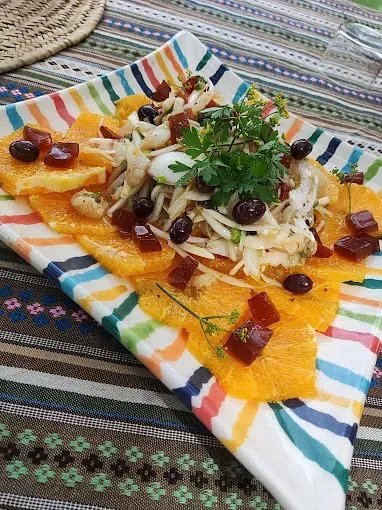 Sobre una mesa hay un plato colorido con ensalada.
