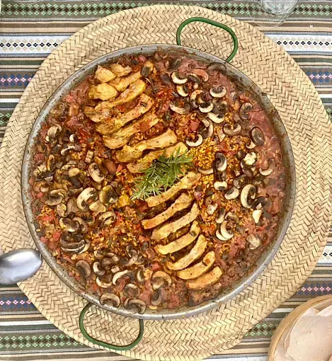 Una sartén con comida reposa sobre un mantel sobre una mesa.