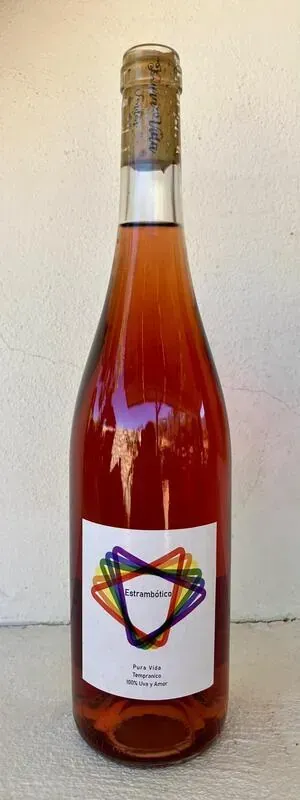 Una botella de vino con un diseño de arcoíris en la etiqueta está sobre una mesa.