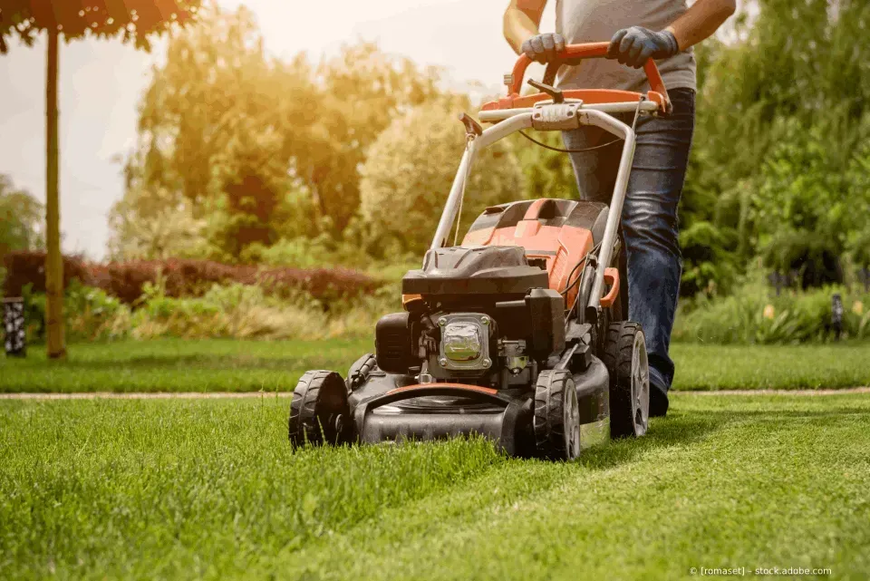 Person beim Rasenmähen