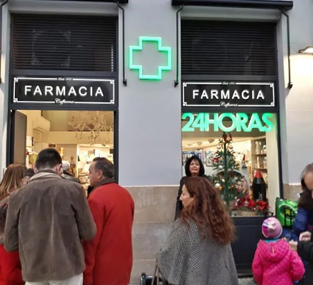 Un grupo de personas paradas afuera de una farmacia
