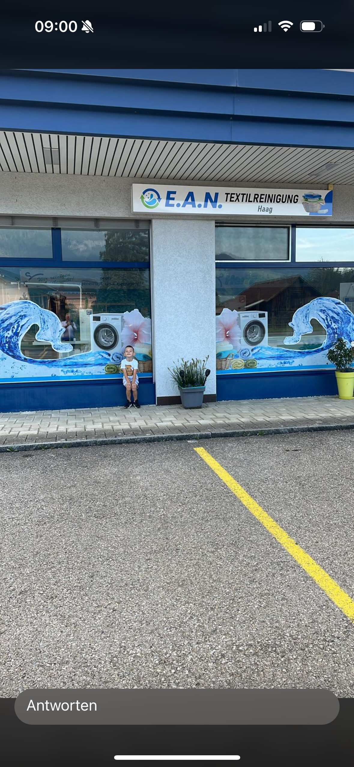 Ein kleiner Junge steht vor einem Waschsalon.