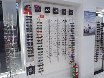 Pared expositora de gafas con filas de monturas y gafas de sol en una óptica