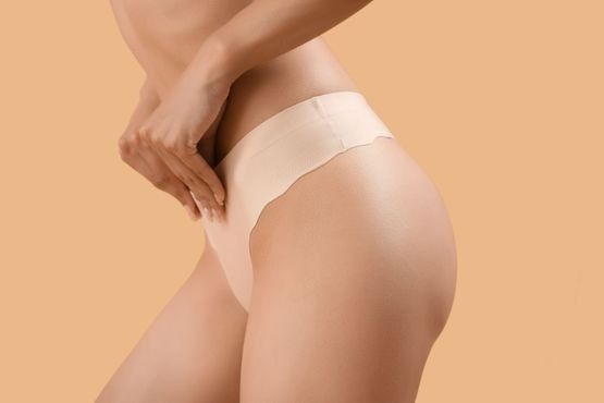 Una mujer lleva un par de tangas sobre un fondo beige.