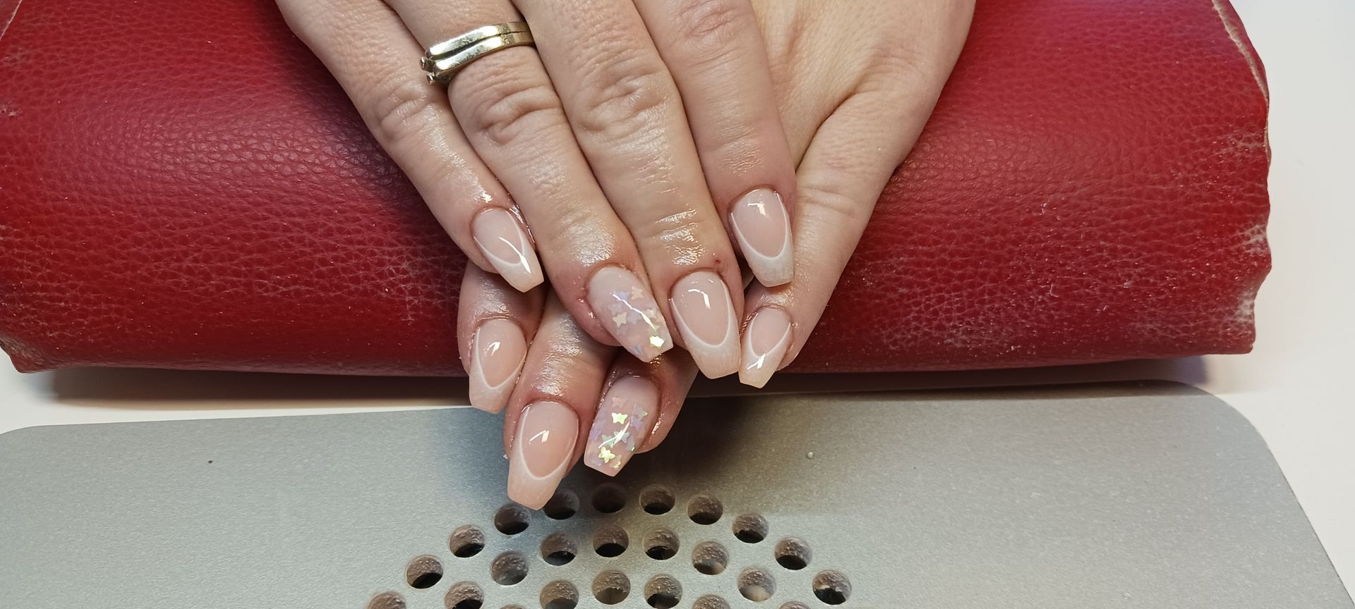 Eine Nahaufnahme der Nägel einer Frau mit einem Ring am Finger.