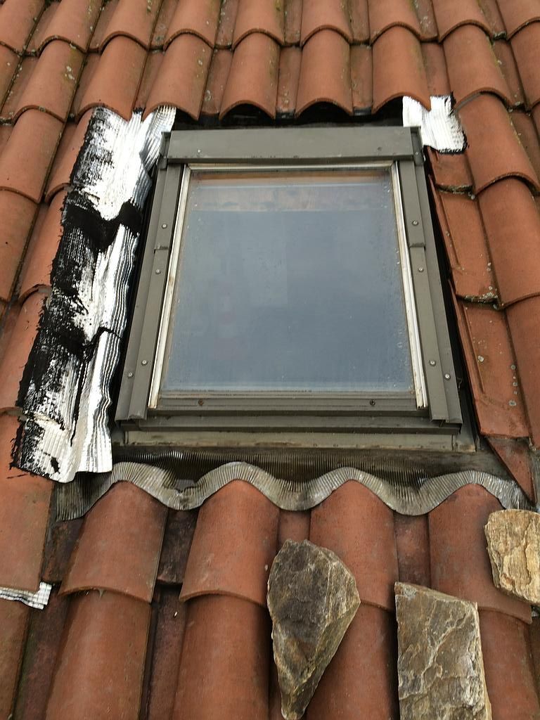 Fenêtre de toit sur des tuiles avec une jointure en zinguerie sale