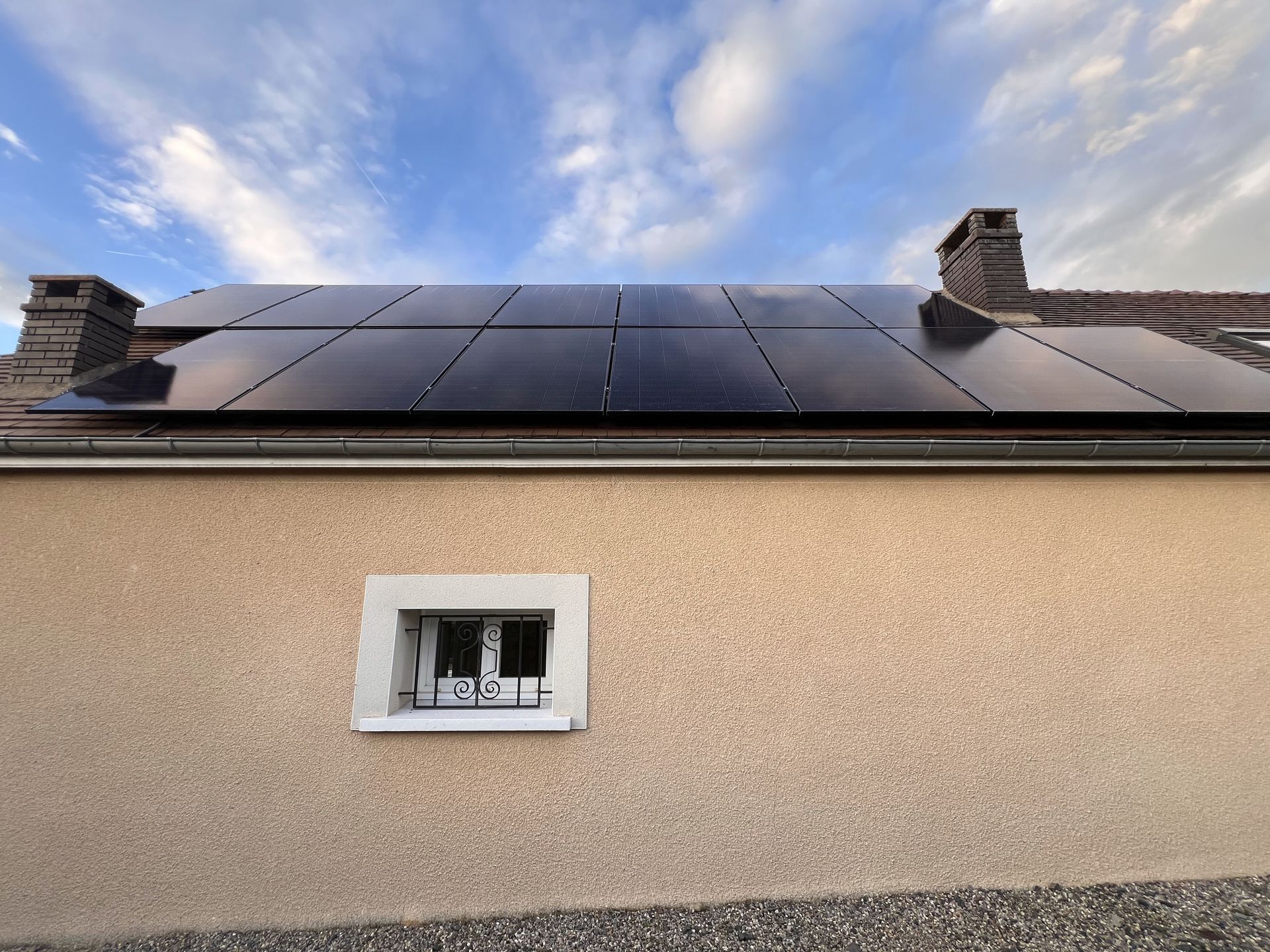 Maison avec une petite fenêtre et des panneaux solaires sur le toit