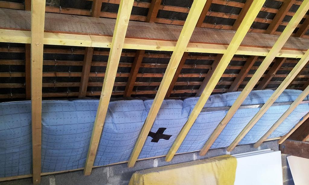 Plaque isolante derrière une charpente de toit