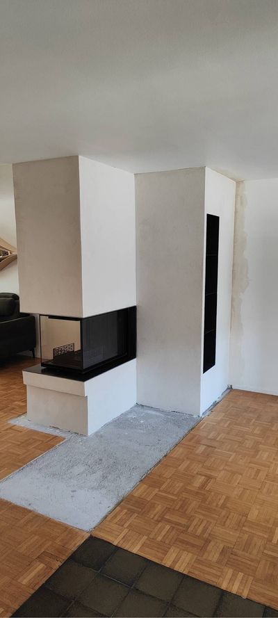 Modernes Wohnzimmer mit weissem Kamin, gefliestem Kaminvorleger und Holzboden