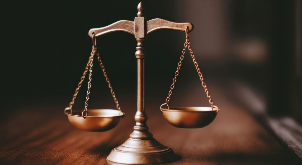 Báscula de latón sobre una mesa de madera, con dos platillos vacíos, sobre un fondo borroso.