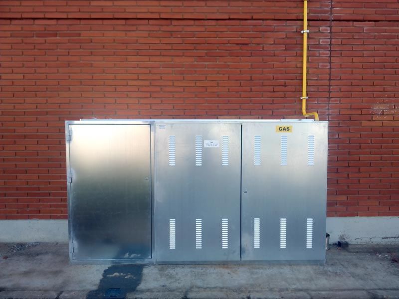 Una pared de ladrillos con una caja de metal delante.