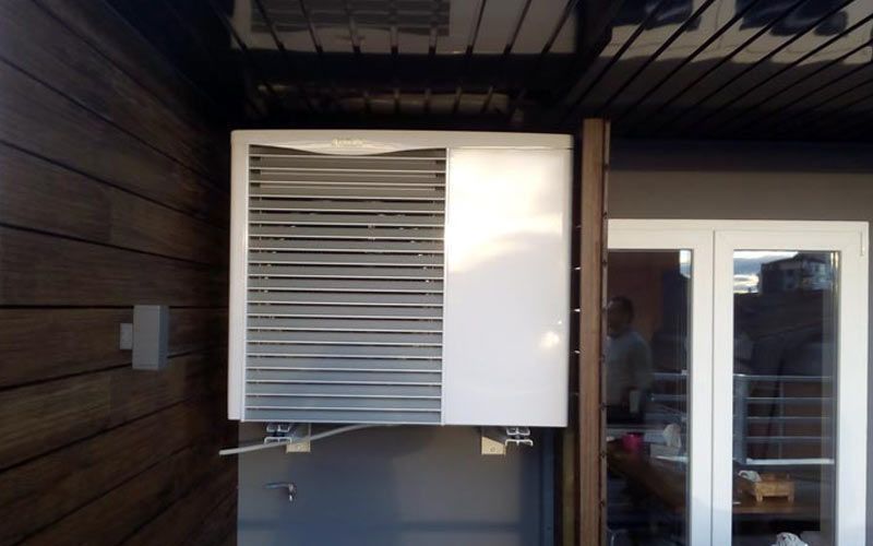 Un acondicionador de aire blanco está montado en el costado de un edificio.