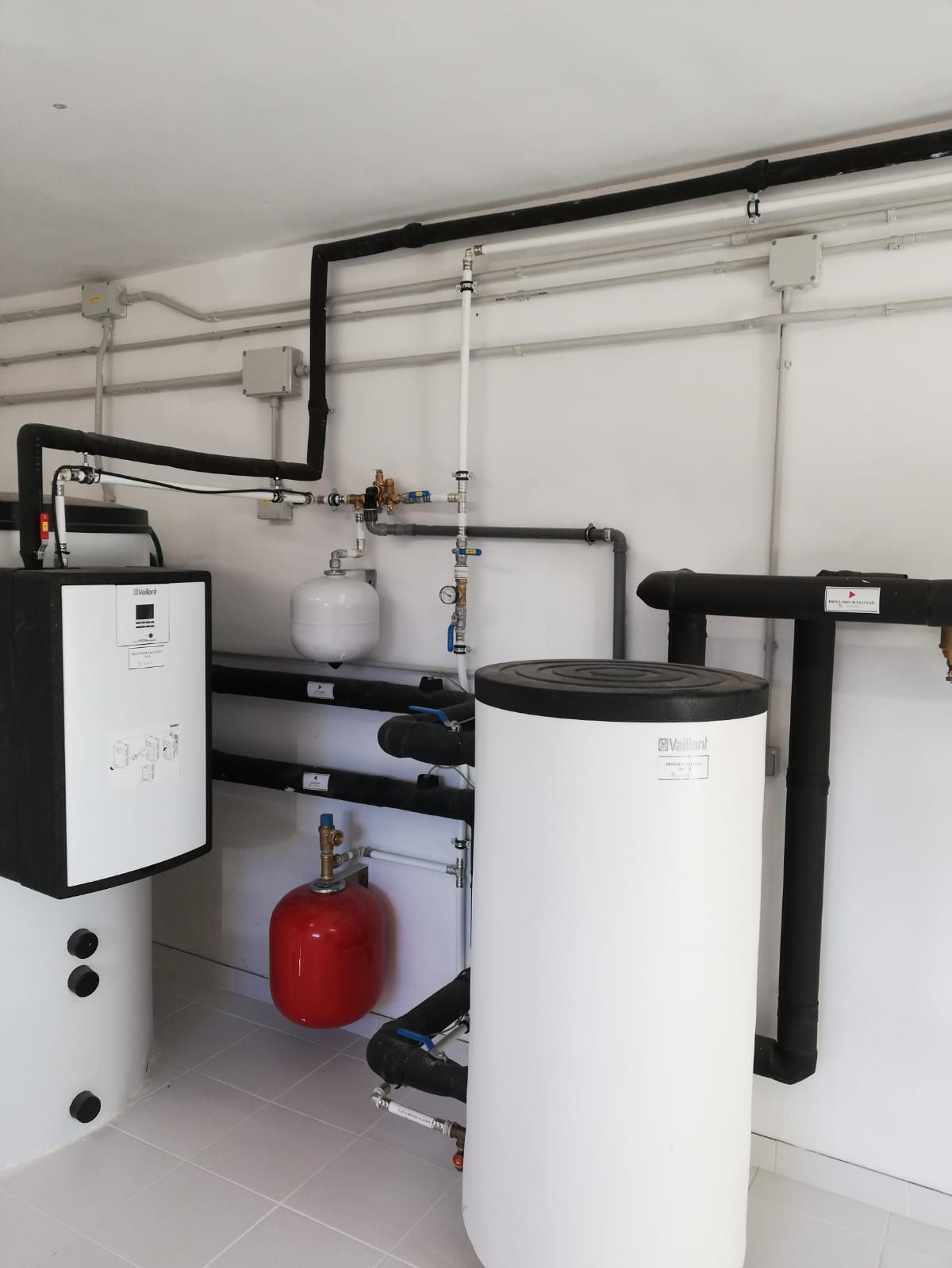 Una habitación con muchas tuberías y un tanque rojo.