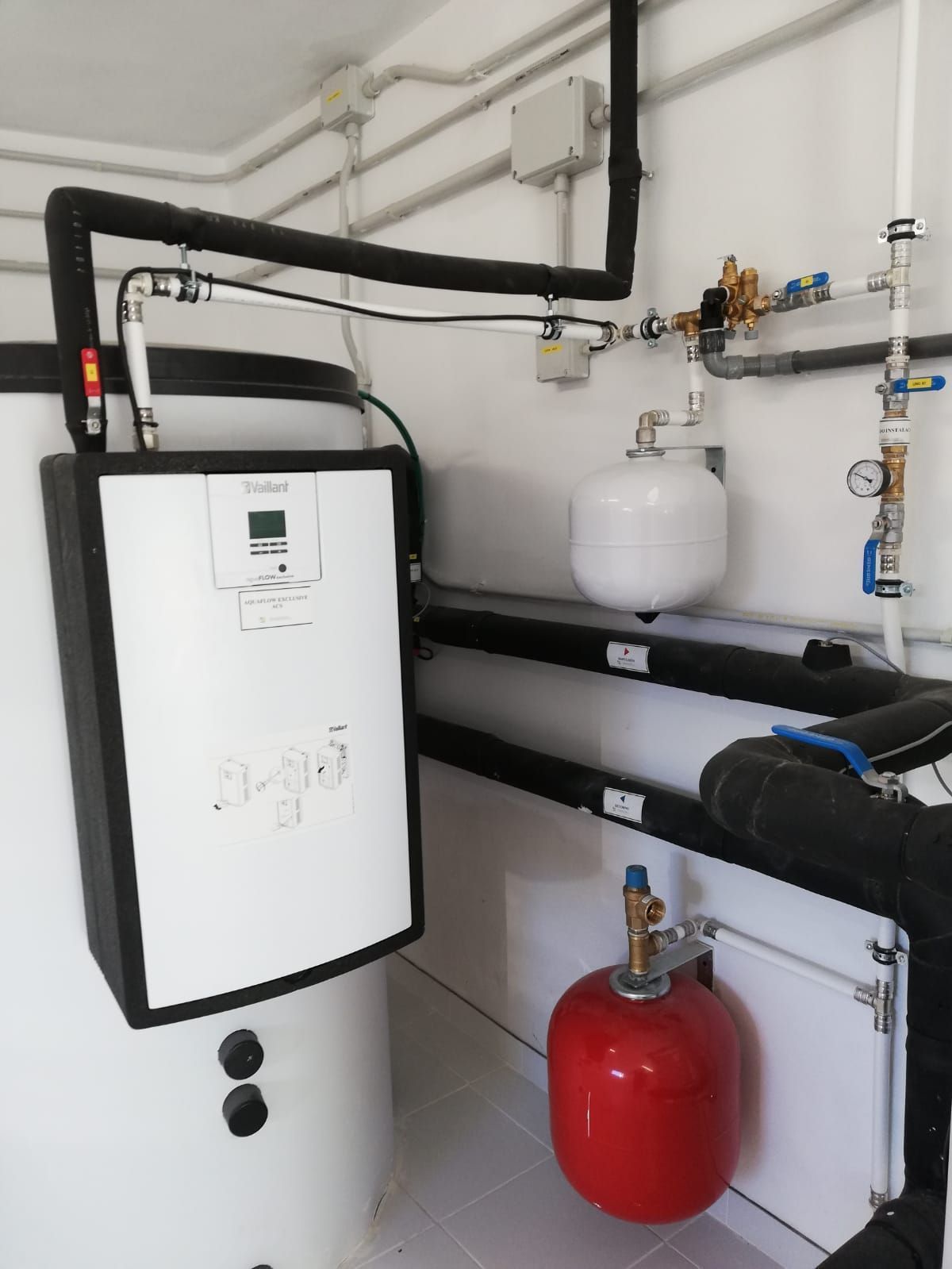 Una habitación con un calentador y un tanque rojo.