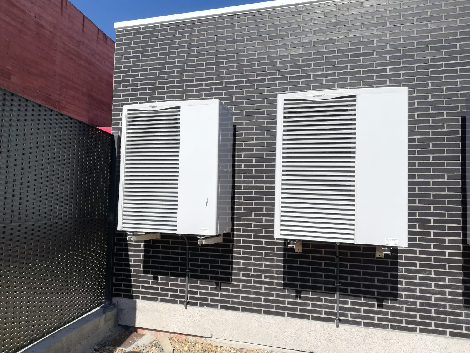 Dos acondicionadores de aire están montados en el lateral de un edificio de ladrillo.