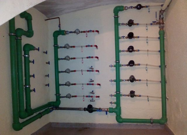 Una habitación con tuberías y válvulas verdes en la pared.