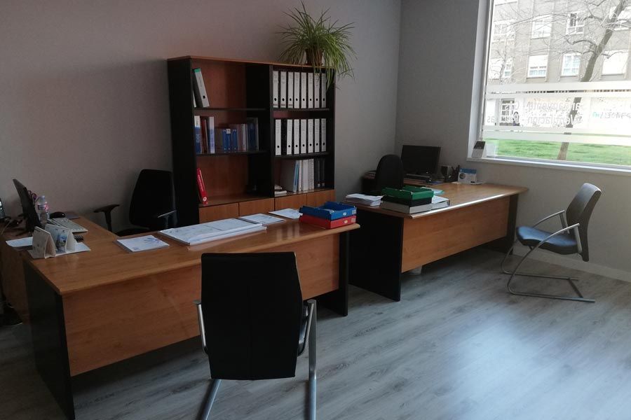 Una habitación con dos escritorios y sillas y una ventana.