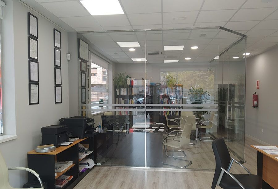 Una habitación con una pared de cristal y un escritorio y sillas.