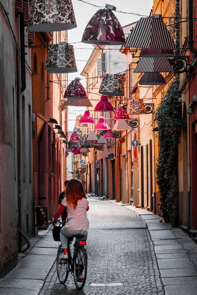 Borghi di Parma con palazzi colorati e ragazza in bicicletta.