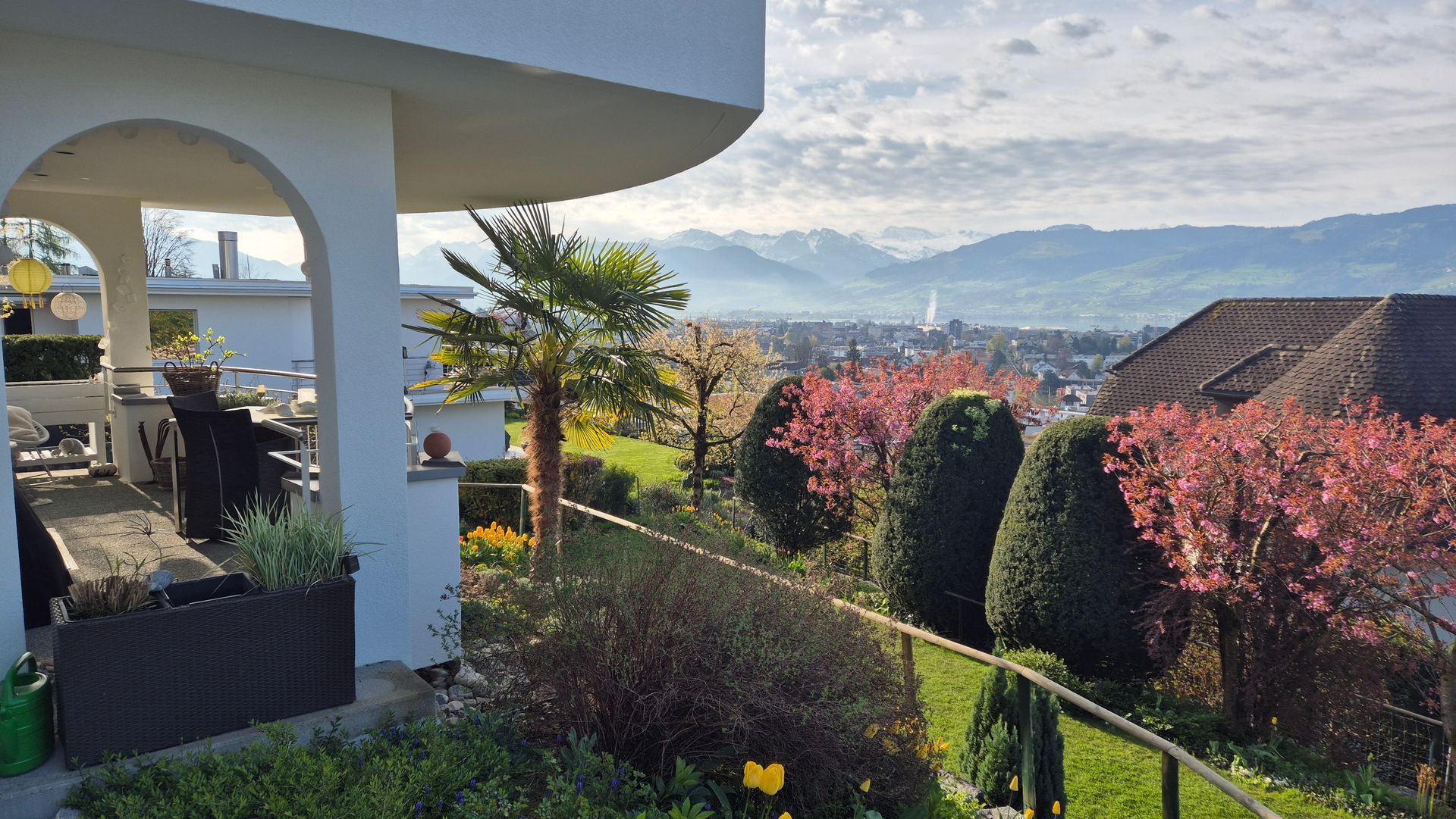 Auf einem Hügel steht ein Haus mit Blick auf die Stadt und die Berge.