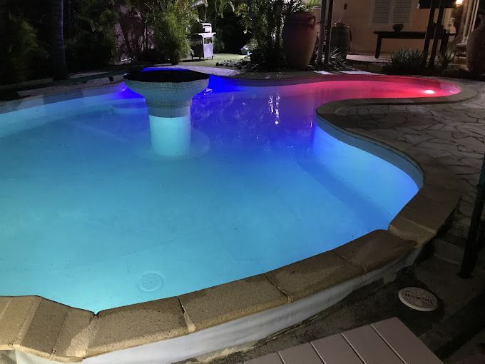 Piscine de nuit avec éclairage de différentes couleurs