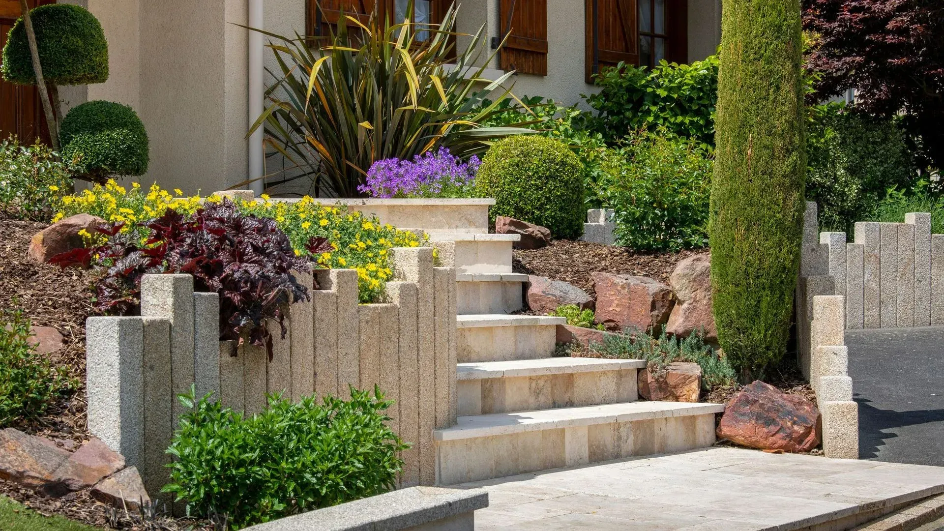 Escalier devant une maison en pierre entouré de petits arbustes