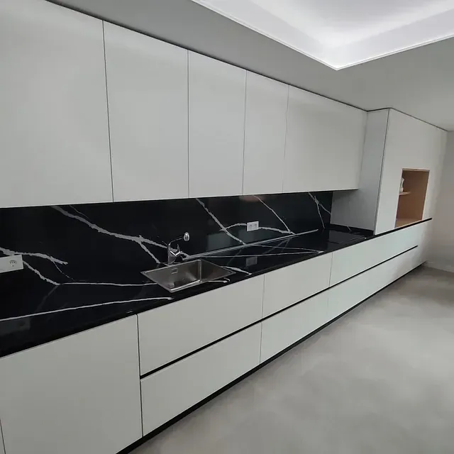 Una cocina con encimeras negras y gabinetes blancos.