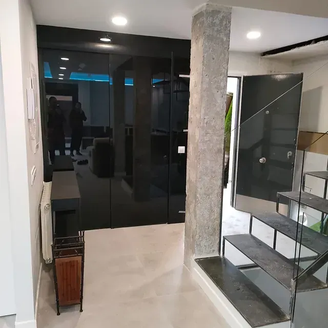 Un pasillo con escaleras y una puerta de cristal.