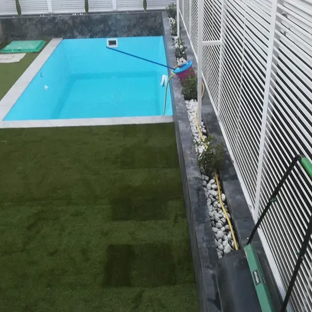 Una gran piscina está rodeada por una valla blanca.