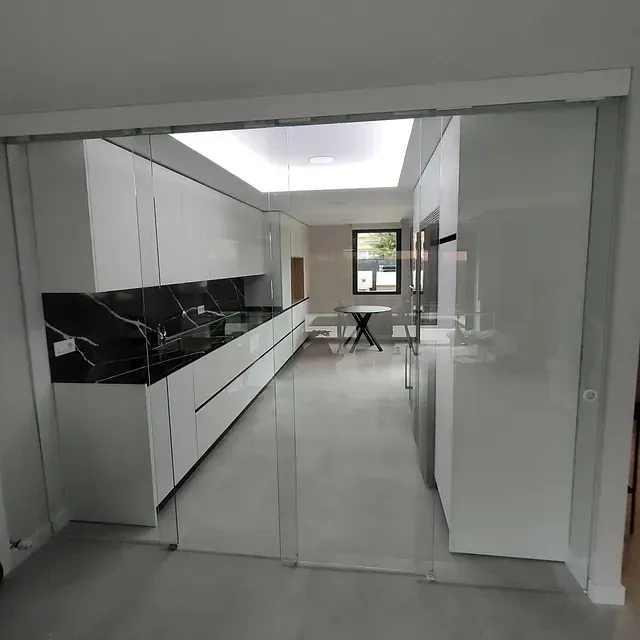 Una cocina con puertas corredizas de vidrio y gabinetes blancos.