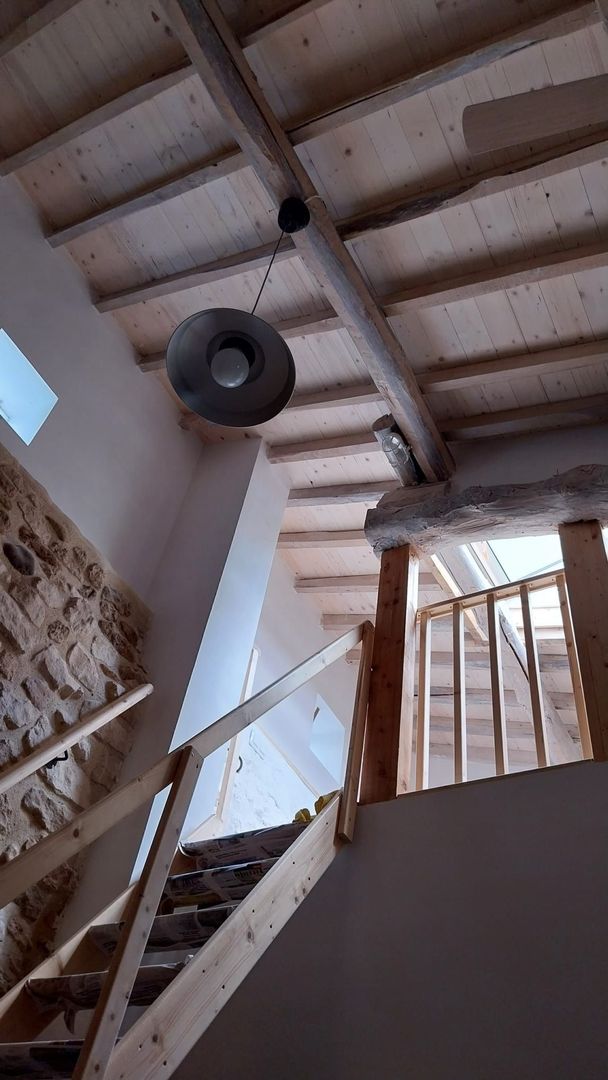 Vista interior de una escalera de madera que conduce a un entrepiso con una lámpara colgando del techo.