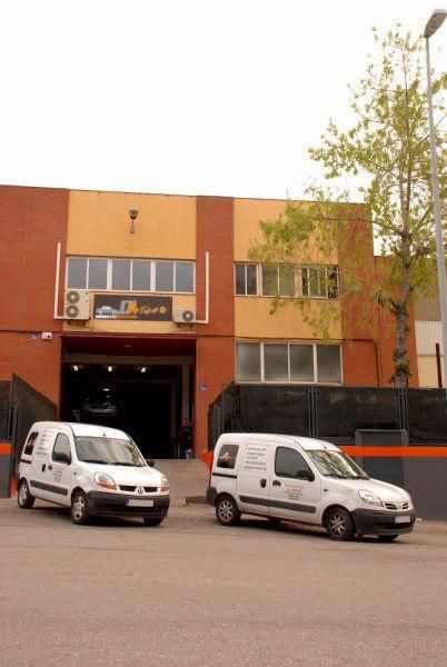 Dos furgonetas blancas están estacionadas frente a un edificio.