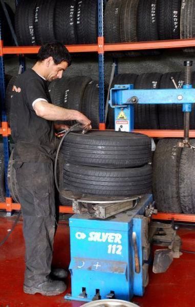 Un hombre está trabajando en un neumático en una máquina plateada 112.