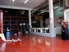 Un garaje con suelo rojo y una carretilla elevadora dentro.