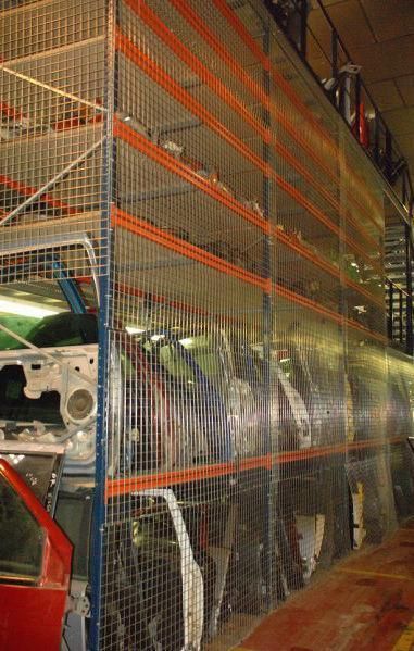 Un almacén lleno de muchas piezas de automóviles detrás de una valla.