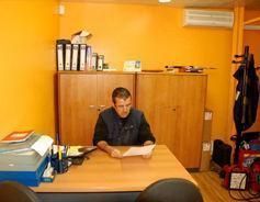 Un hombre está sentado en un escritorio en una oficina mirando un trozo de papel.