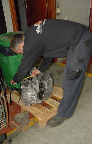 Un hombre está midiendo un motor en una paleta de madera.