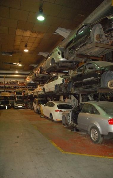 Un montón de coches están apilados uno encima del otro en un garaje.