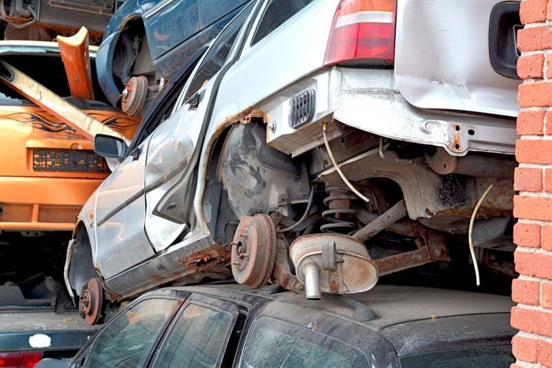 Un montón de coches están apilados uno encima del otro en un depósito de chatarra.