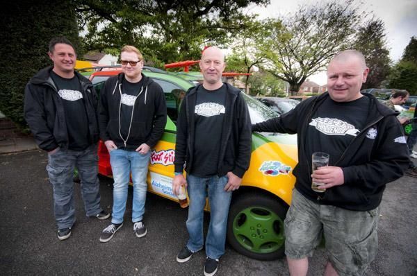 Un grupo de hombres de pie frente a un coche colorido.