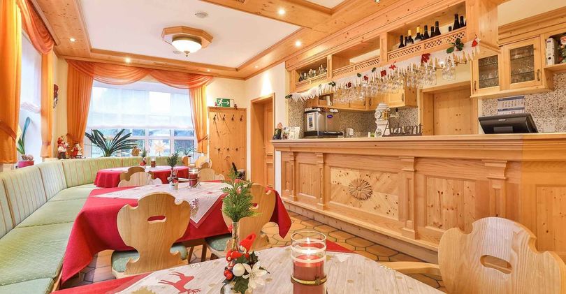 Gemütliches Esszimmer im Landhausstil mit Holzbar, Tischdekoration und Sonnenlicht durch ein Fenster