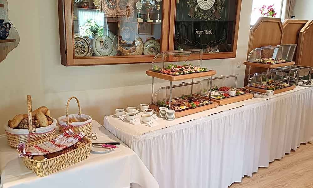 Dessertbuffet mit Gebäck, Obstplatten und Weidenkörben in einem hellen Speisesaal