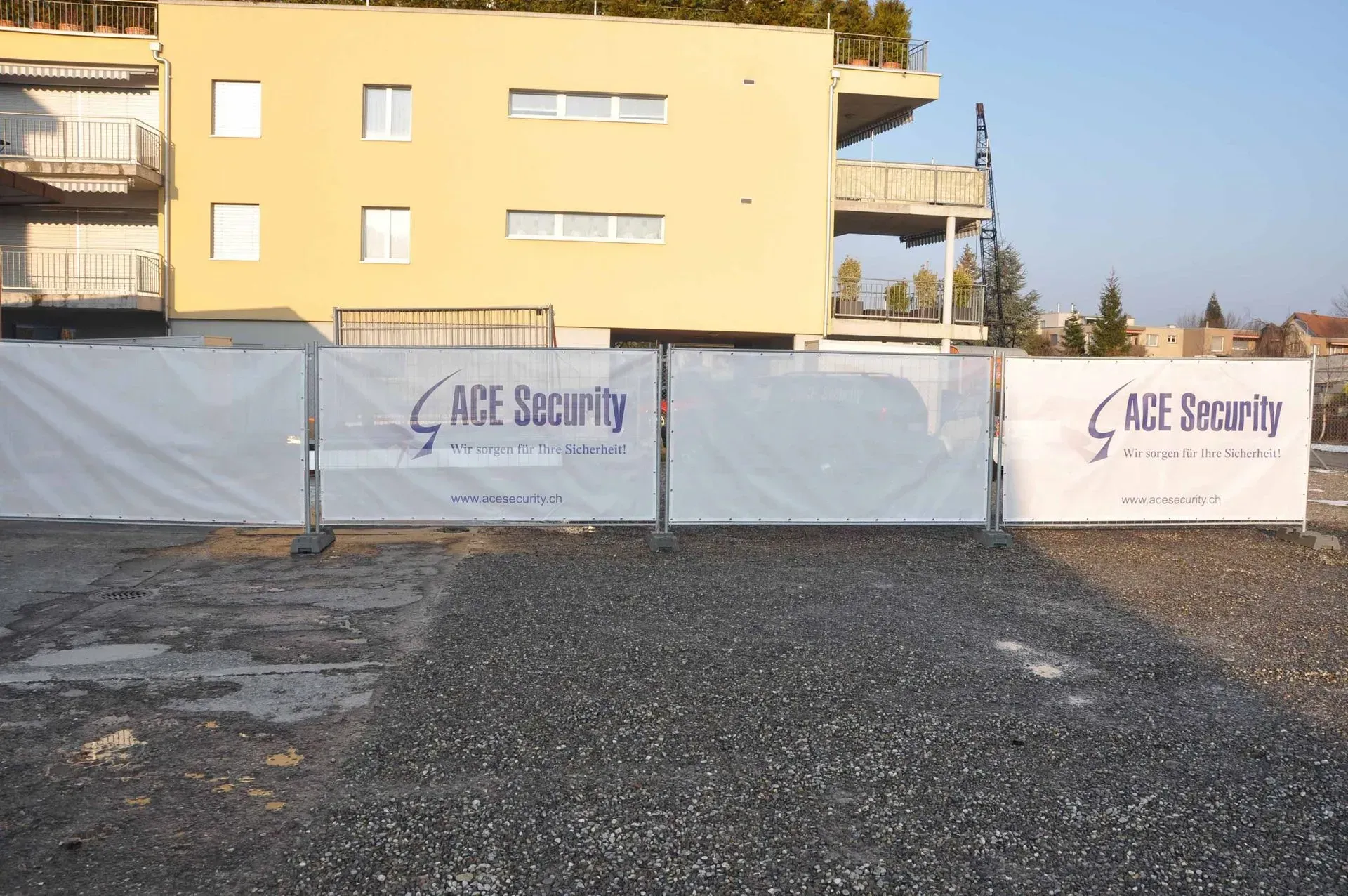 Abgesperrte Baustelle mit weißen Sicherheitsbannern vor einem gelben Wohnhaus